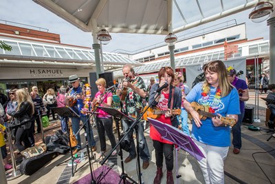 Love Wirral Festival at the Pyramids Shopping Centre, Birkenhead. Wirral Ukulele Orchestra perform in front of the crowds.