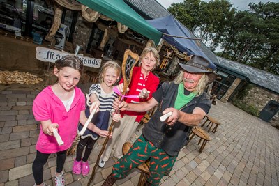 Bodnant Weksh Food Childrens Festival.Brigid Coffey from Rhos on Sea with her two twin grandchildren Caoimhe and Ailbhe Coffey are shown how to use a magic wand by Mal the Woodman from The Old Chapel in Mold.