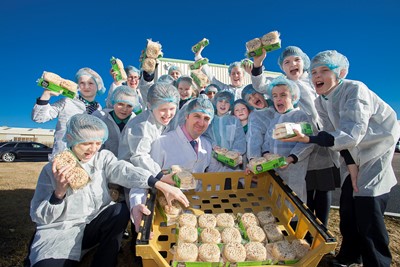 VILLAGE BAKERY, WREXHAM. Pupils from Wood Memorial CP school, Saltney during a visit to the Village Bakery, Wrexham. Photographed is Matty Owens of the Village Bakery handing out free crumpets to the pupils.